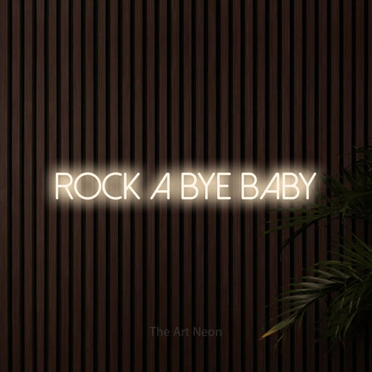 Warm white LED neon sign reading "Rock a Bye Baby" against dark wooden slats