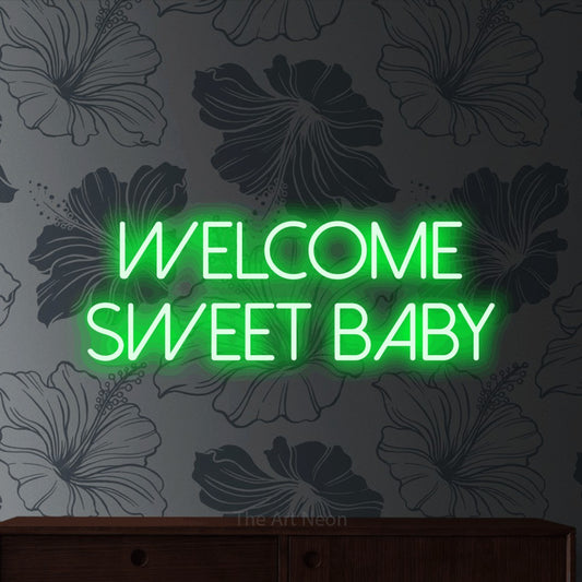 Green LED neon sign reading "Welcome Sweet Baby" against grey floral wallpaper