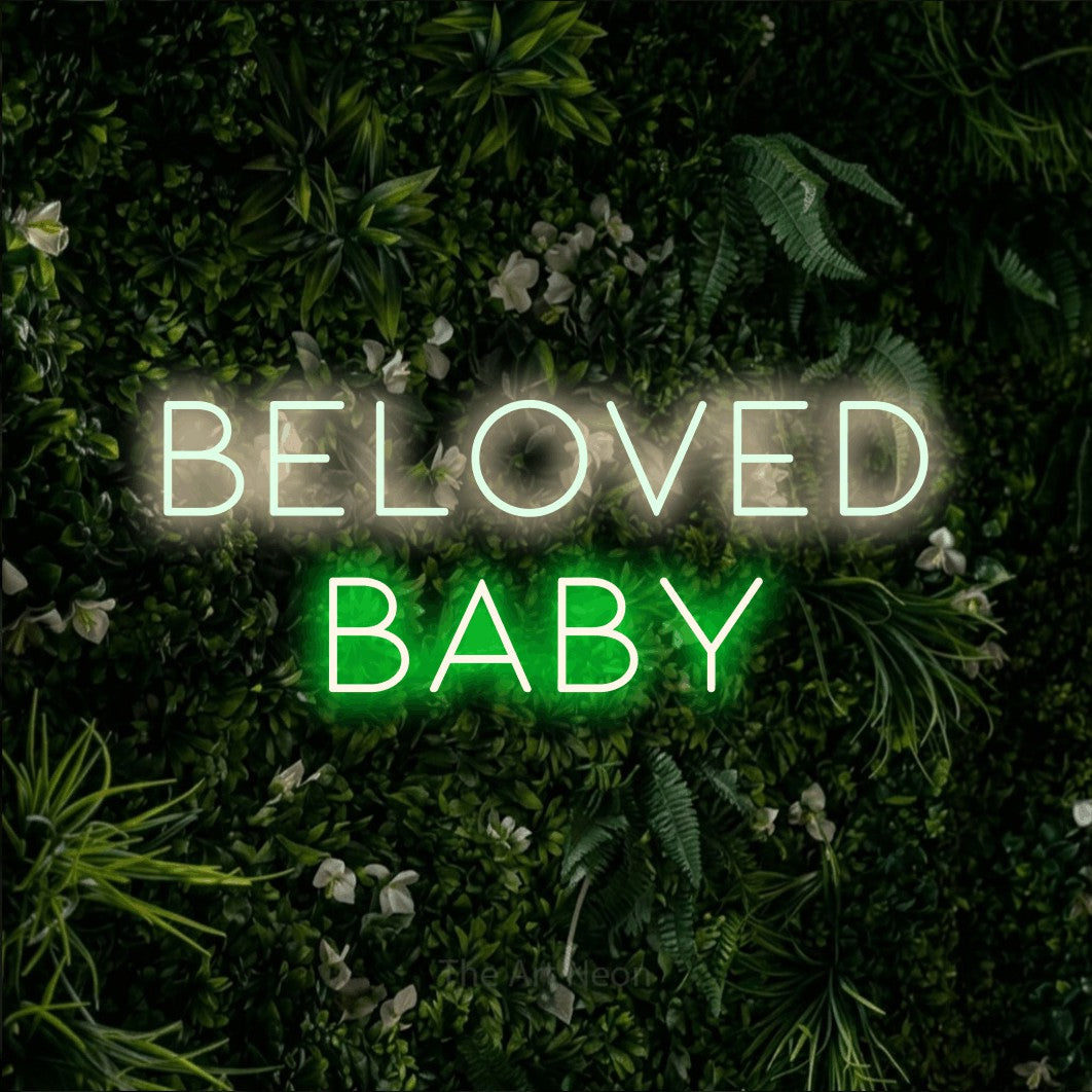 Green and warm white LED neon sign reading "Beloved Baby" against a leafy green wall