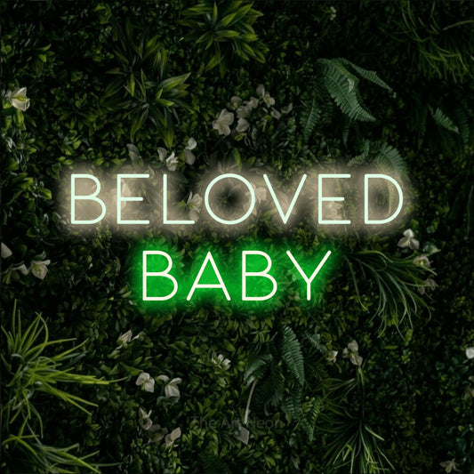 Green and warm white LED neon sign reading "Beloved Baby" against a leafy green wall