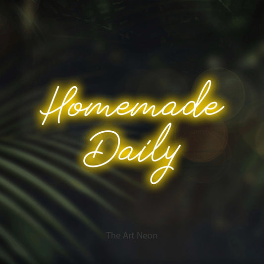Yellow script-style LED neon sign reading "Homemade Daily" against dark blurred palm leaves for restaurant décor