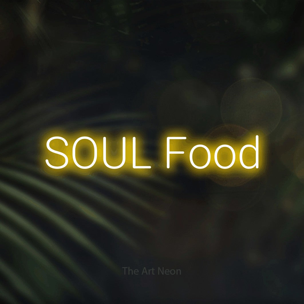 Yellow LED neon sign reading "Soul Food" against dark blurred palm leaves for restaurant décor
