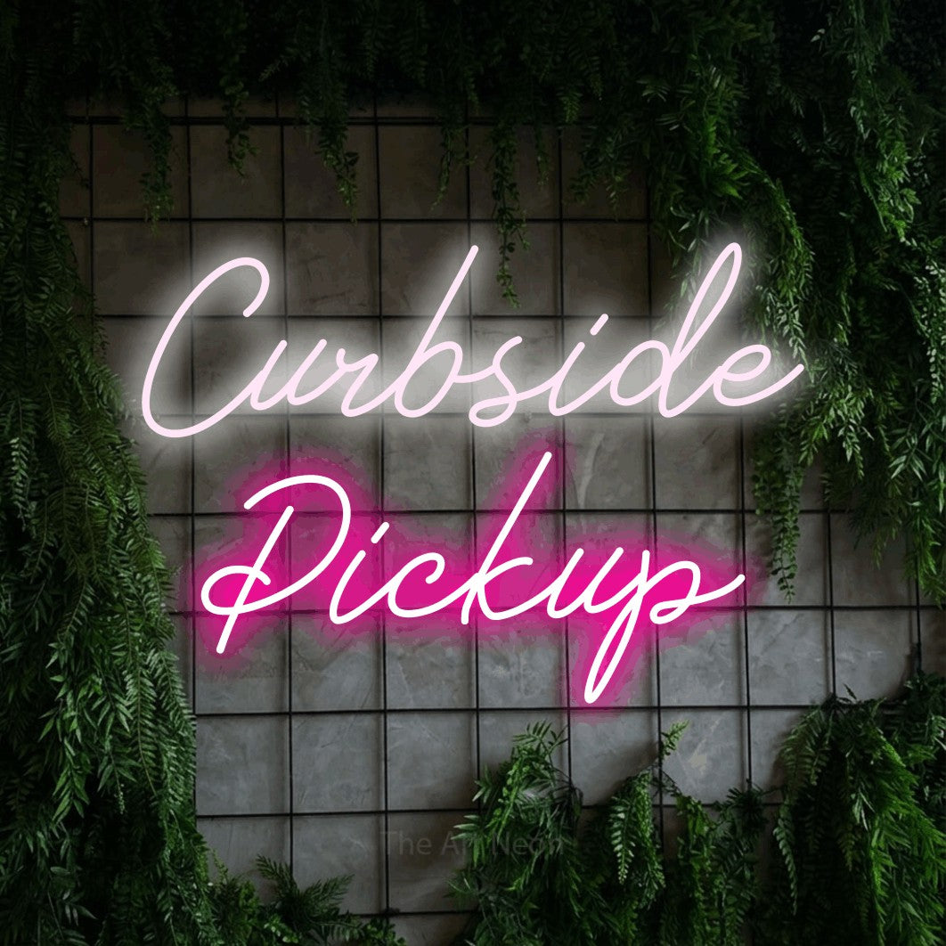 Hot pink and cool white script-style LED neon sign reading "Curbside Pickup" against a green grid wall with foliage