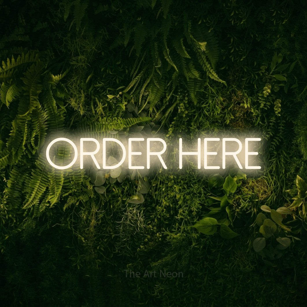 Warm white LED neon sign reading "Order Here" against a moss-covered green wall for restaurant décor