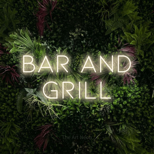 Warm white LED neon sign reading "Bar and Grill" against a lush garden wall with pink flowers for restaurant décor