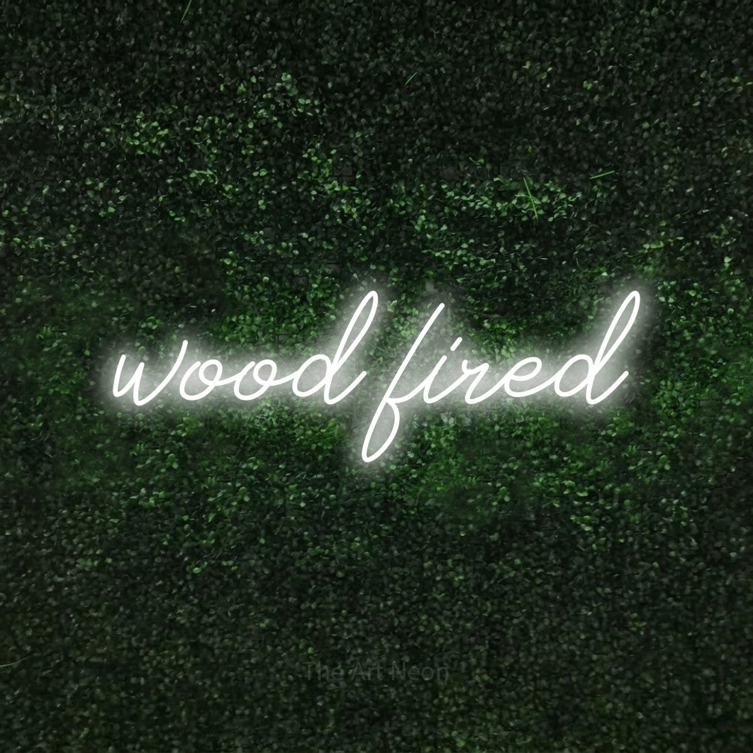 Cool white script-style LED neon sign reading "Wood Fired" against a textured green moss wall for restaurant décor