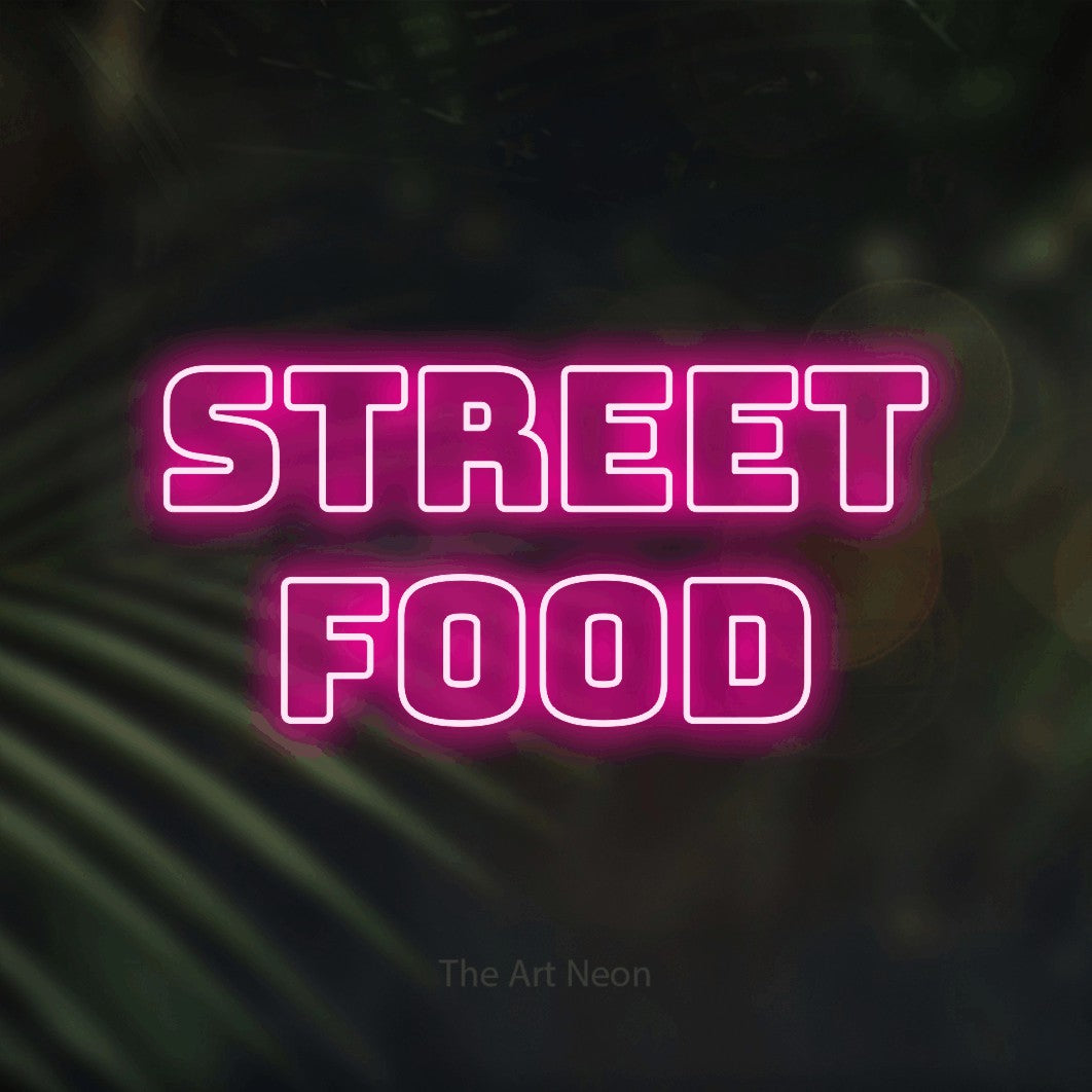 Hot pink outline-style LED neon sign reading "Street Food" against dark blurred palm leaves for restaurant décor