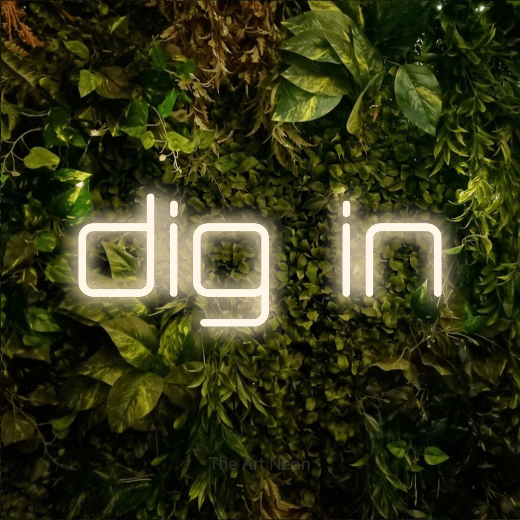 Warm white LED neon sign reading "Dig In" against a textured moss and foliage wall for restaurant décor
