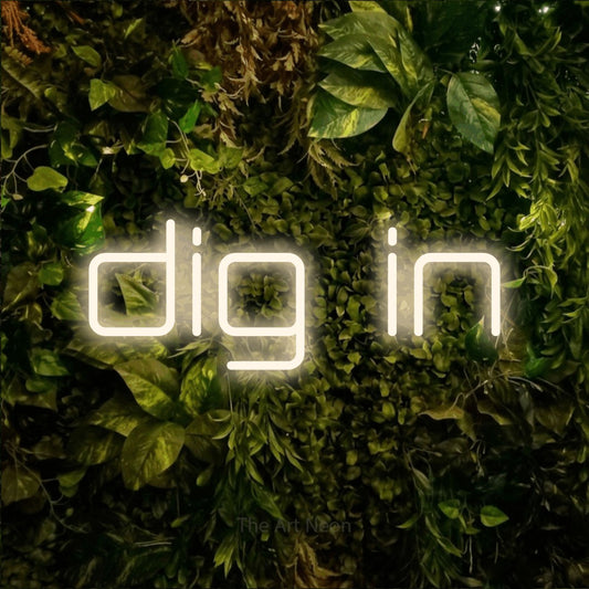 Warm white LED neon sign reading "Dig In" against a textured moss and foliage wall for restaurant décor