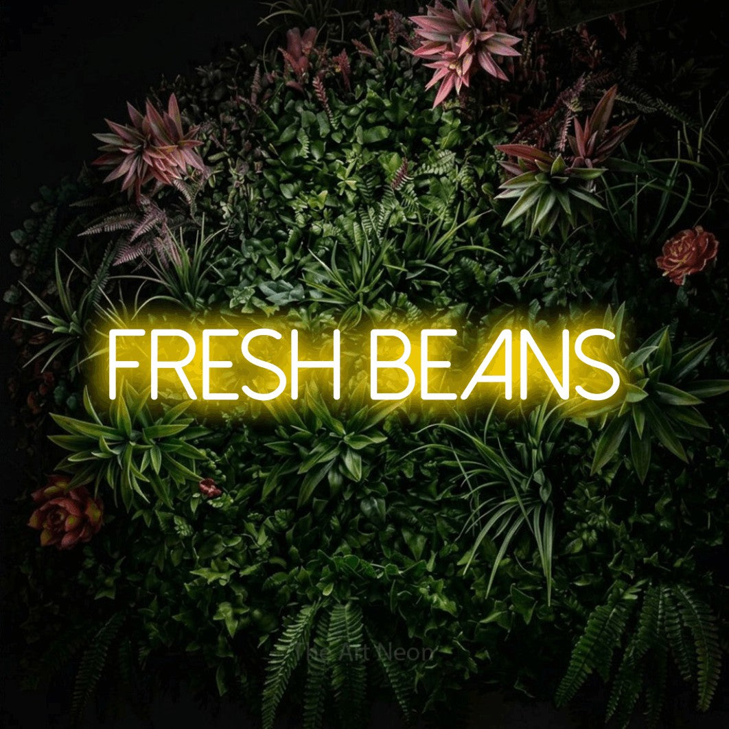 Yellow LED neon sign reading "Fresh Beans" against a flowering garden wall for café décor