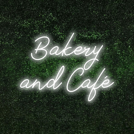 Cool white script-style LED neon sign reading "Bakery and Café" against a textured green moss wall for café décor