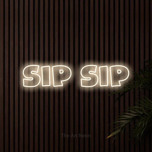 Warm white outline-style LED neon sign reading "Sip Sip" against dark wooden slats for café décor