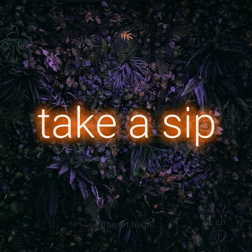 Orange LED neon sign reading "Take a Sip" against a purple floral wall for café décor