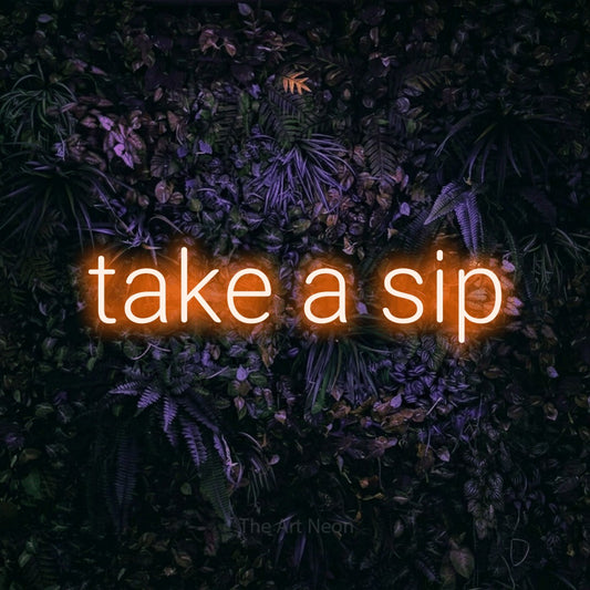 Orange LED neon sign reading "Take a Sip" against a purple floral wall for café décor