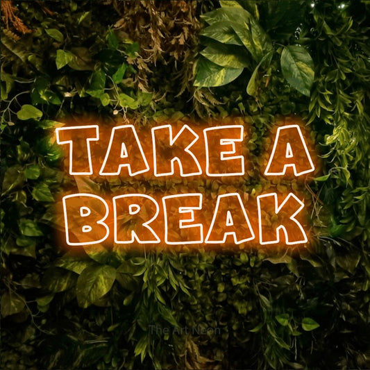 Orange outline-style LED neon sign reading "Take a Break" against a textured moss and foliage wall for café décor