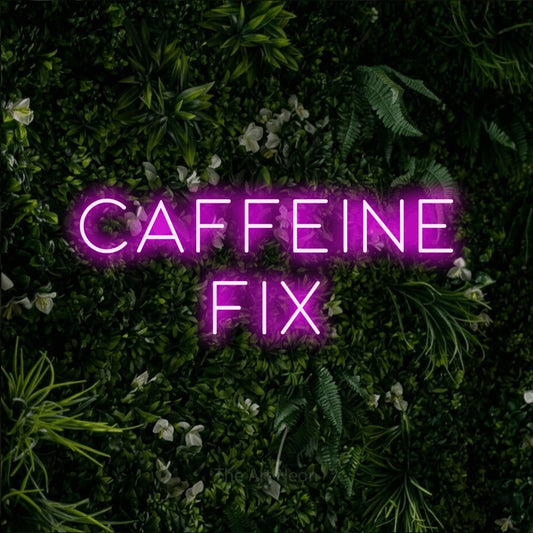 Pink LED neon sign reading "Caffeine Fix" against a leafy green wall for café décor