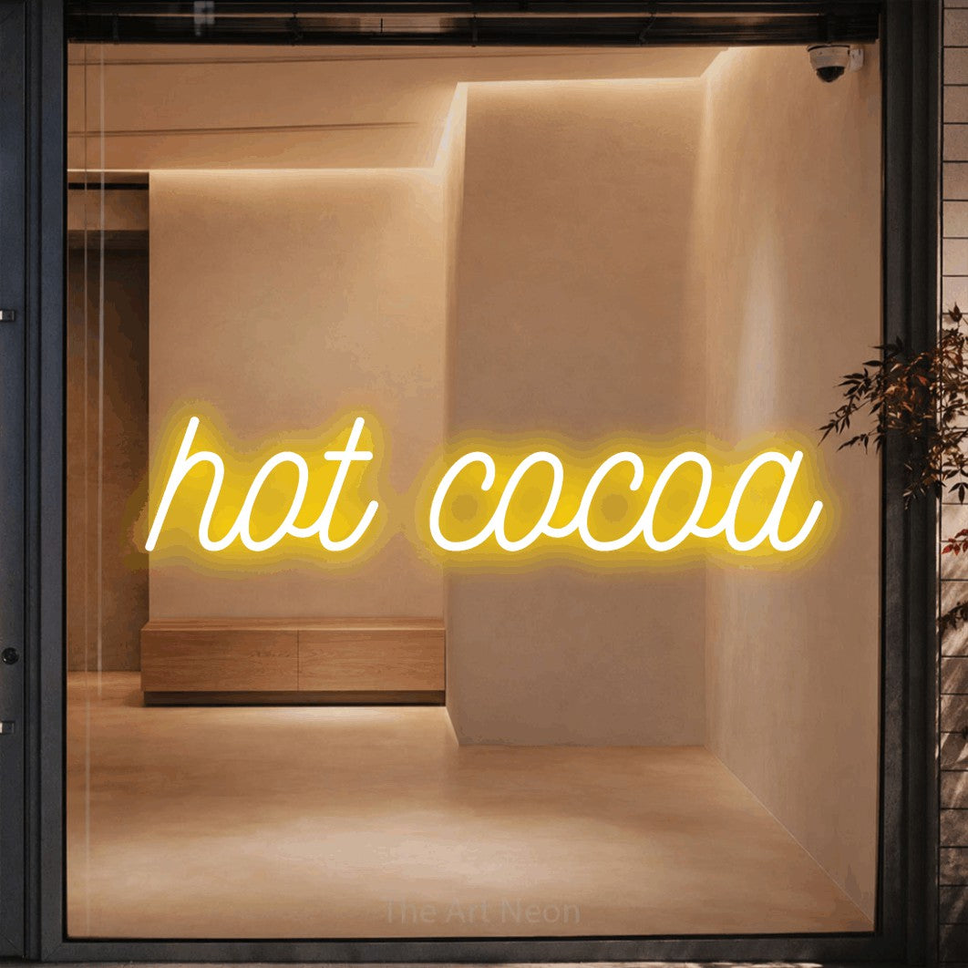 Yellow script-style LED neon sign reading "Hot Cocoa" against a warm beige alcove wall for café décor