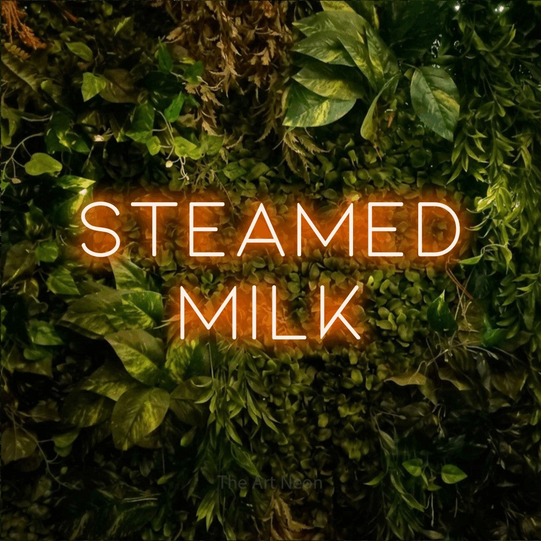 Orange LED neon sign reading "Steamed Milk" against a textured moss and foliage wall for café décor
