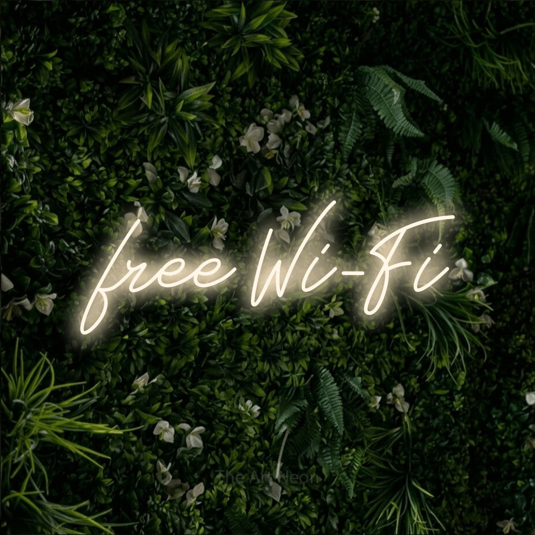 Warm white script-style LED neon sign reading "Free Wi-Fi" against a leafy green wall for café décor
