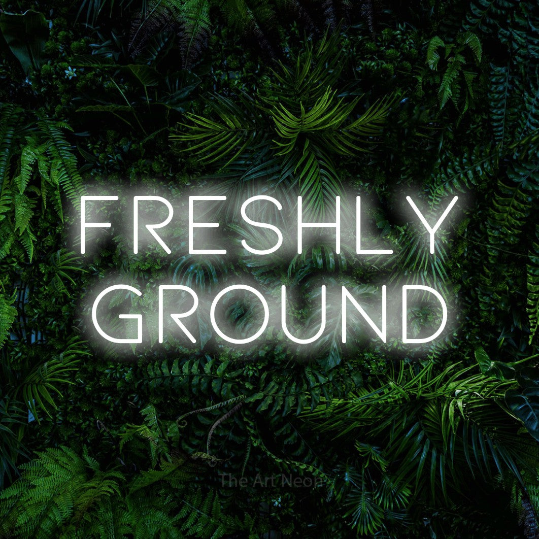 Cool white LED neon sign reading "Freshly Ground" against a dense tropical foliage wall for café décor