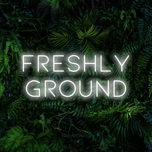 Cool white LED neon sign reading "Freshly Ground" against a dense tropical foliage wall for café décor