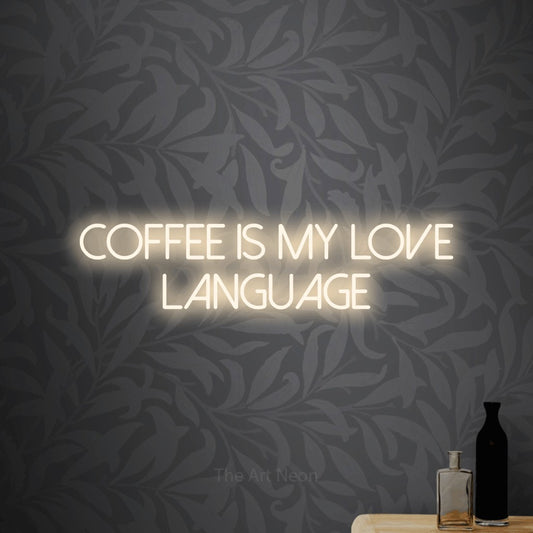 Warm white LED neon sign reading "Coffee is My Love Language" against light grey floral wallpaper for café décor