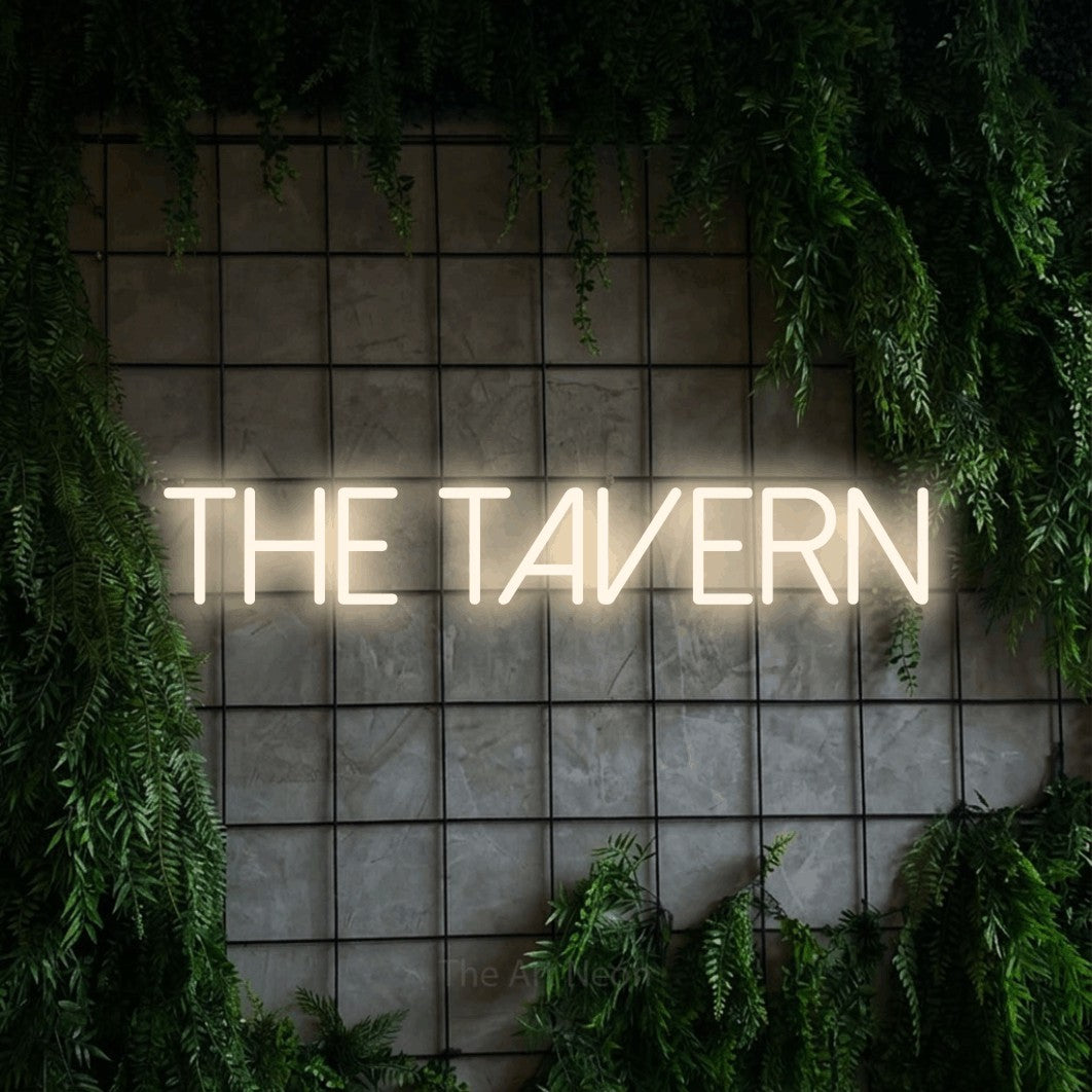 Enseigne néon à DEL à lumière blanche chaude, affichant « The Tavern » sur un mur quadrillé vert avec du feuillage, pour décorer un bar