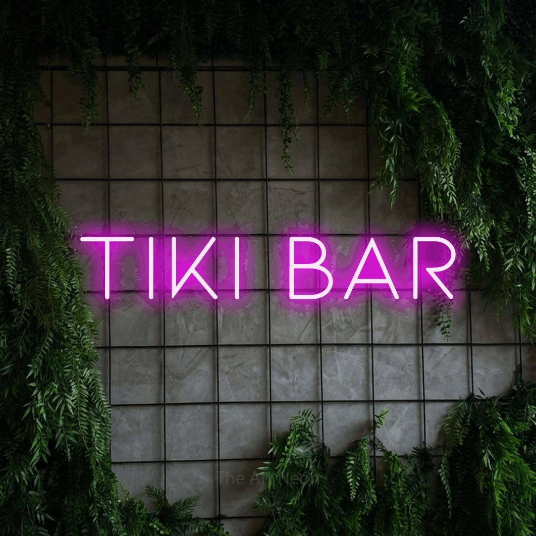 Pink LED neon sign reading "Tiki Bar" against a green grid wall with foliage for bar décor