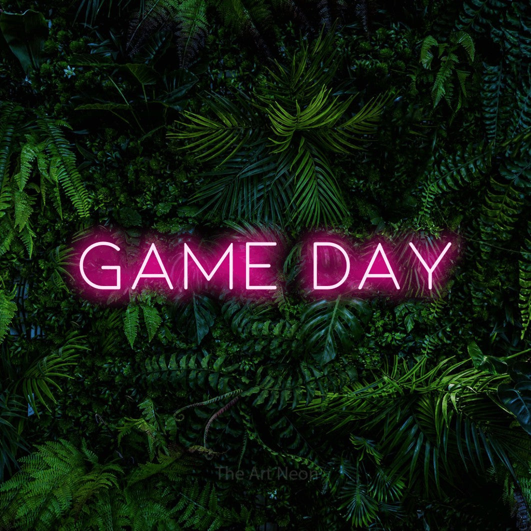 Hot pink LED neon sign reading "Game Day" against a dense tropical foliage wall for bar décor