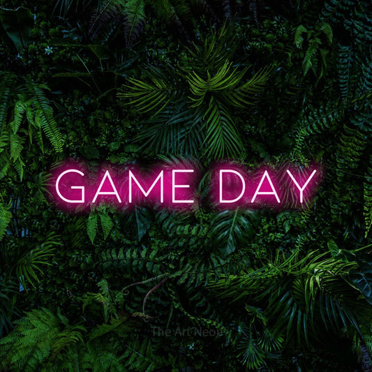 Enseigne néon à DEL à lumière rose vif, affichant « Game Day » sur un mur de feuillage tropical dense, pour décorer un bar