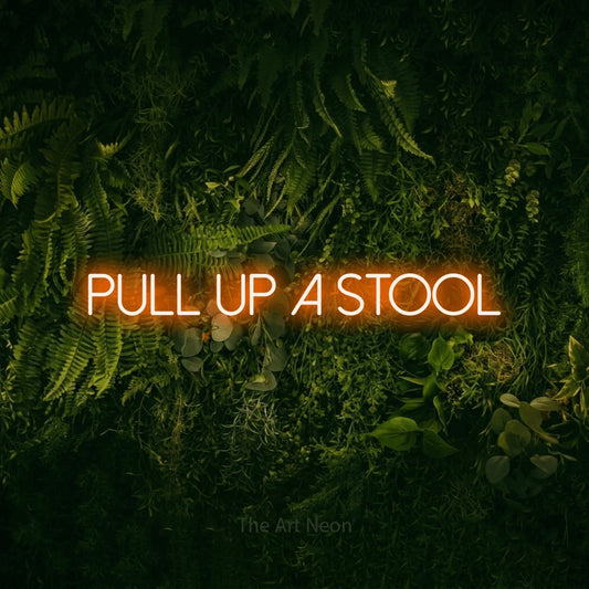 Orange LED neon sign reading "Pull Up a Stool" against a moss-covered green wall for bar décor