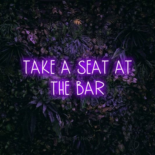 Purple LED neon sign reading "Take a Seat at the Bar" against a purple floral wall for bar décor