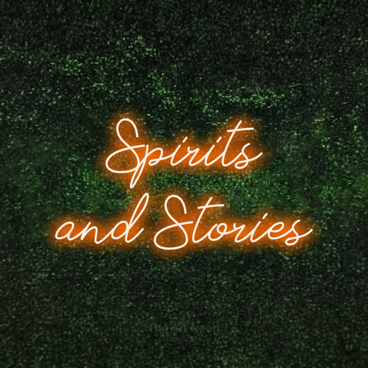 Orange script-style LED neon sign reading "Spirits and Stories" against a textured green moss wall for bar décor