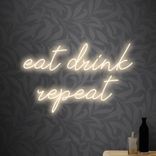 Warm white script-style LED neon sign reading "Eat Drink Repeat" against light grey floral wallpaper for bar décor