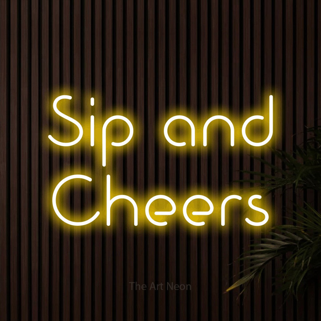 Yellow LED neon sign reading "Sip and Cheers" against dark wooden slats for bar décor