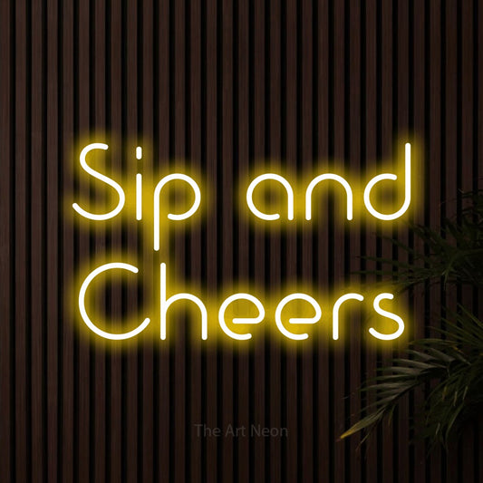 Yellow LED neon sign reading "Sip and Cheers" against dark wooden slats for bar décor