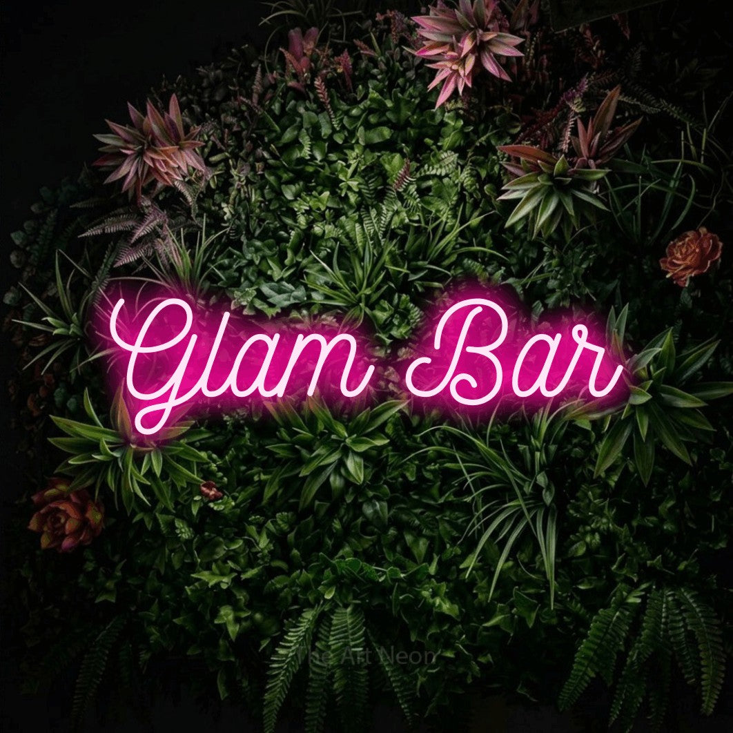 Hot pink script-style LED neon sign reading "Glam Bar" against a flowering garden wall for salon décor