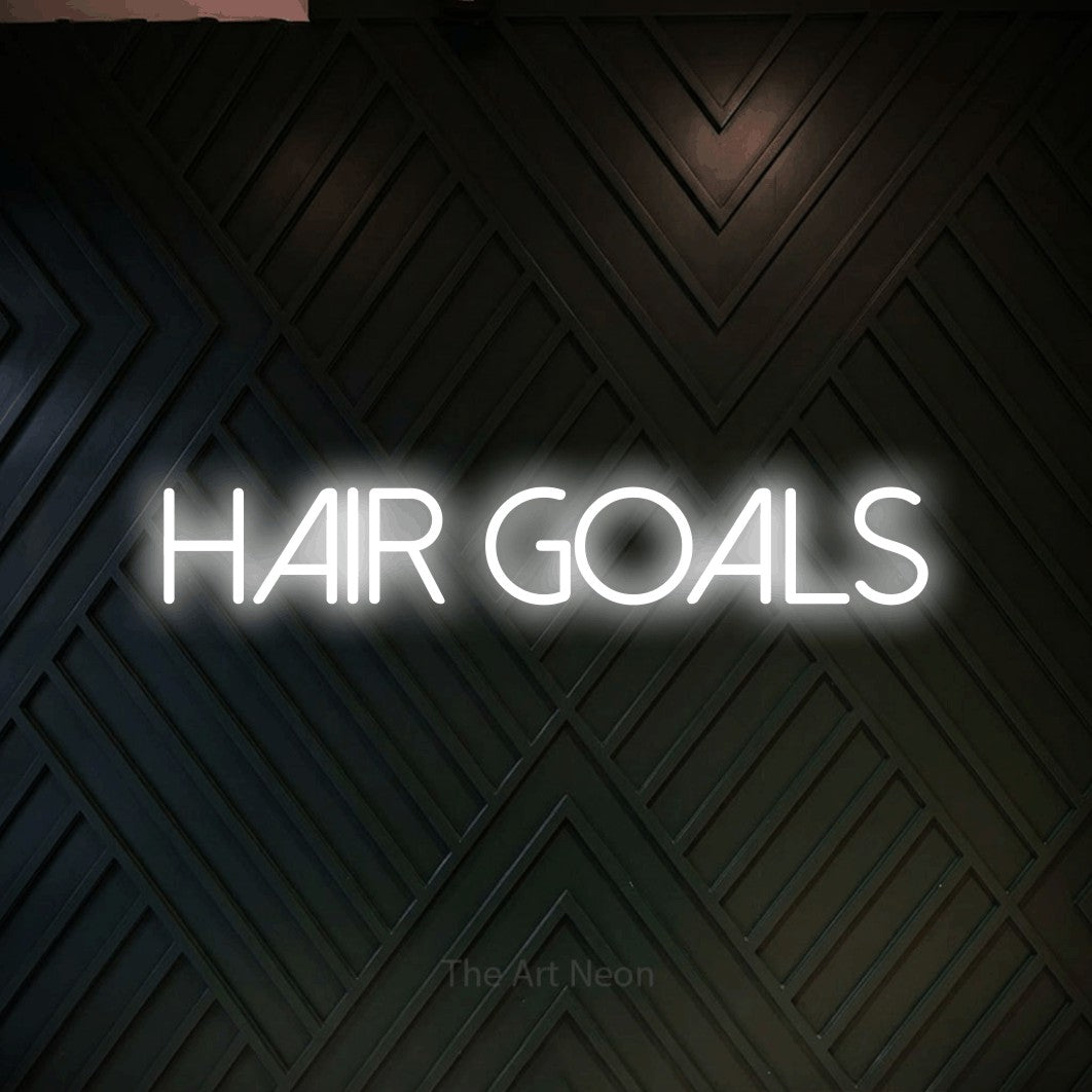 Cool white LED neon sign reading "Hair Goals" against a dark geometric wood wall for salon décor