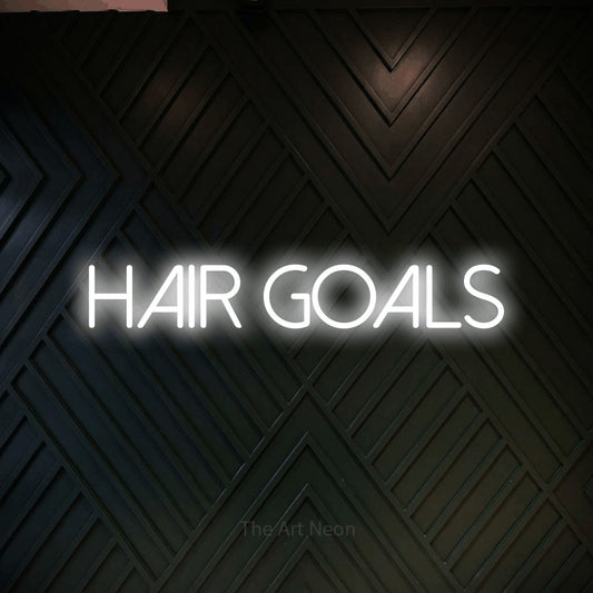 Cool white LED neon sign reading "Hair Goals" against a dark geometric wood wall for salon décor