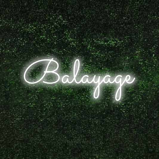 Cool white LED neon sign reading "Balayage" against a textured green moss wall for salon décor