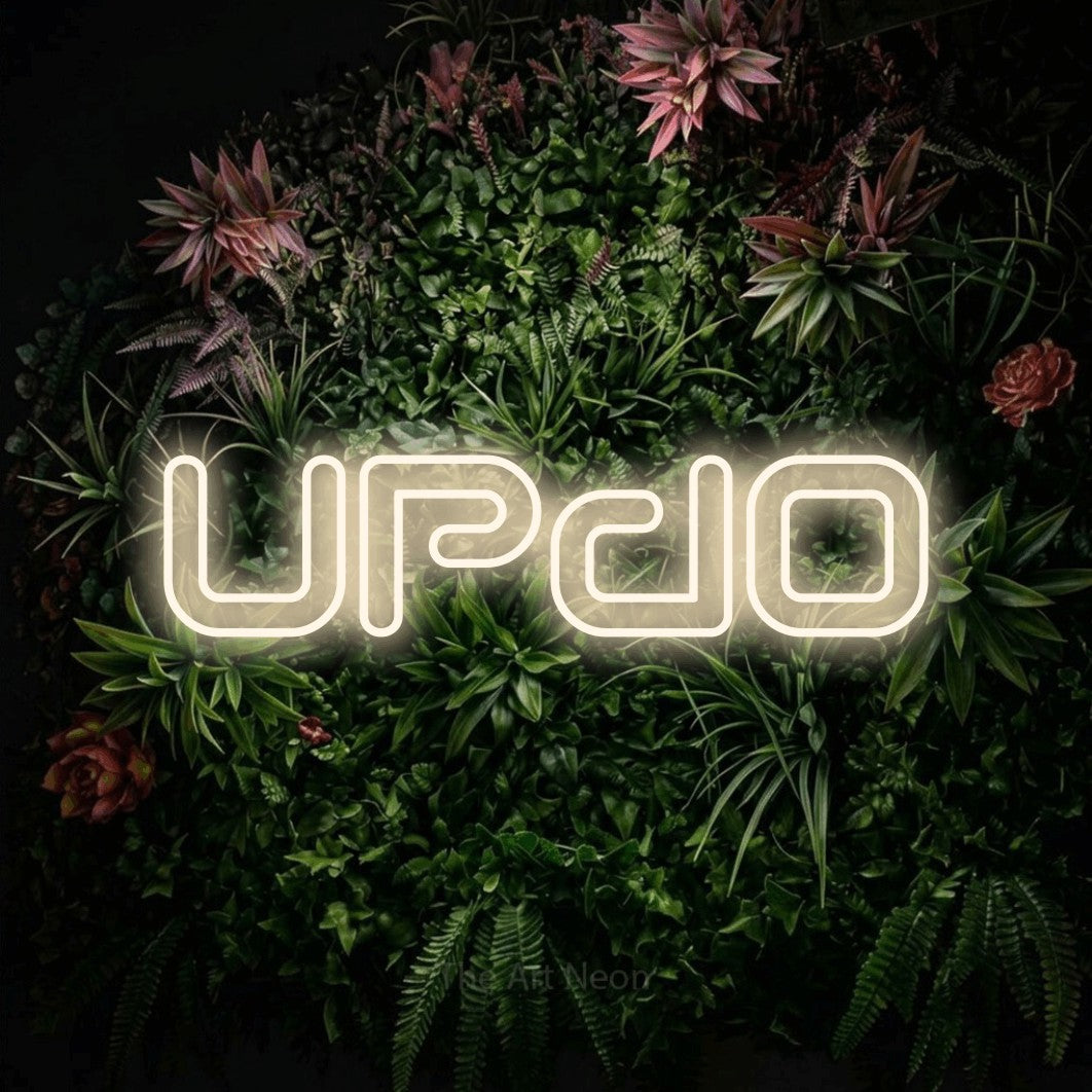 Warm white outline-style LED neon sign reading "Updo" against a flowering garden wall for salon décor