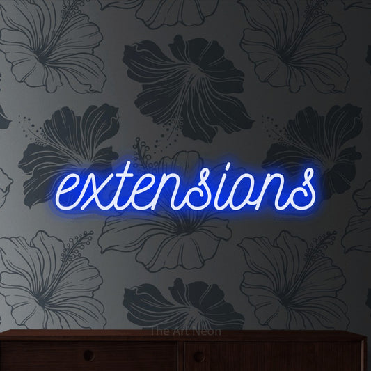 Blue script-style LED neon sign reading "Extensions" against grey floral wallpaper for salon décor