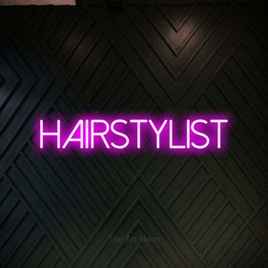 Pink LED neon sign reading "Hairstylist" against a dark geometric wood wall for salon décor