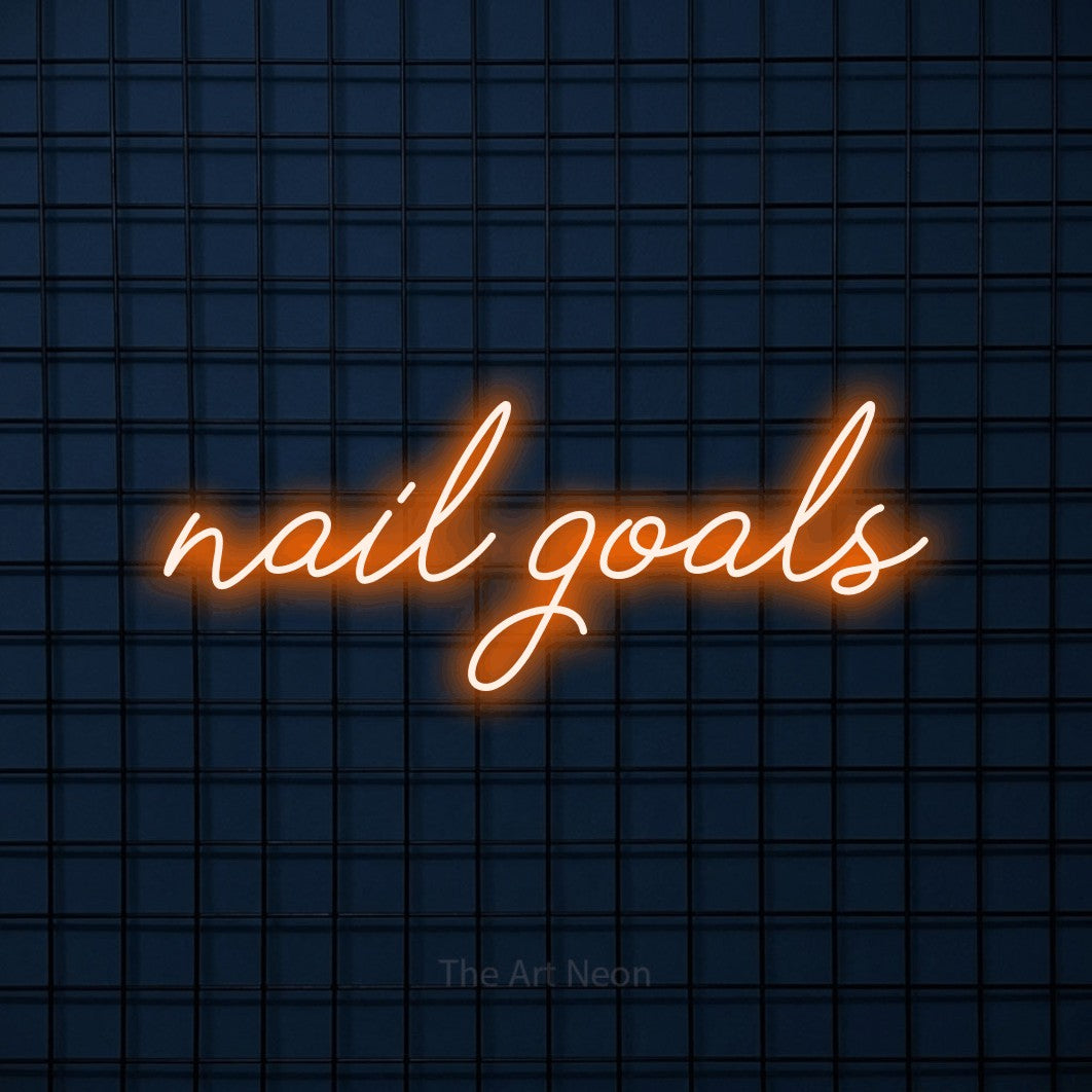 Orange script-style LED neon sign reading "Nail Goals" against a dark blue tiled wall for salon décor