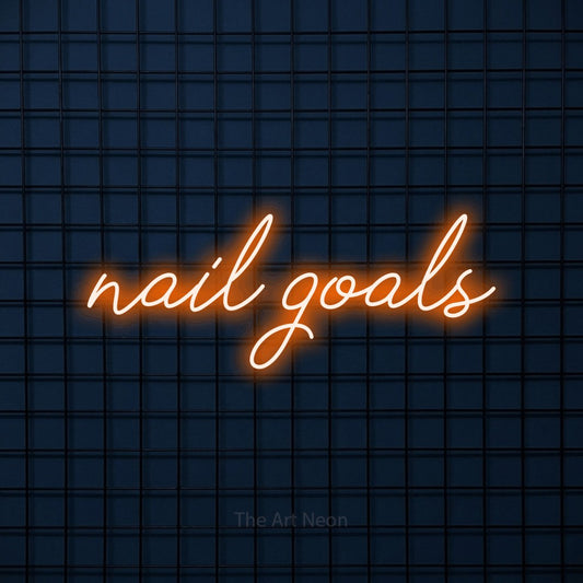 Orange script-style LED neon sign reading "Nail Goals" against a dark blue tiled wall for salon décor