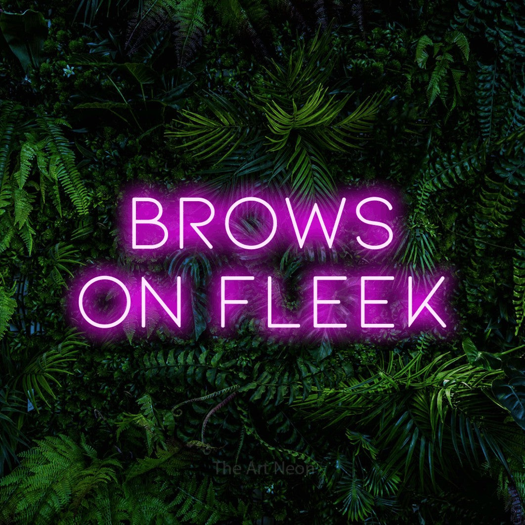 Pink LED neon sign reading "Brows on Fleek" against a dense tropical foliage wall for salon décor