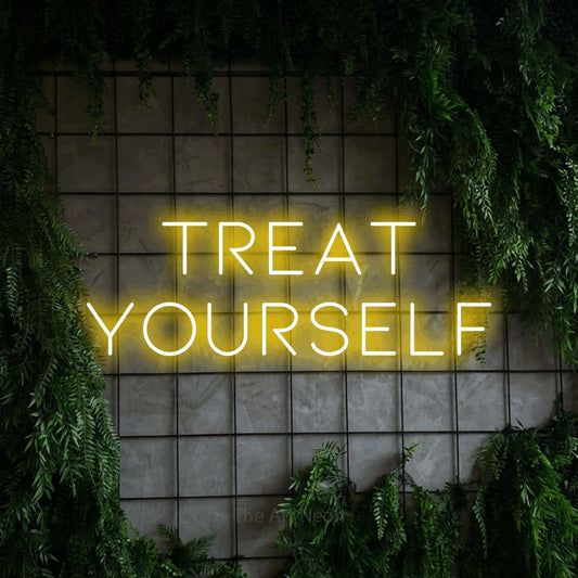 Yellow LED neon sign reading "Treat Yourself" against a green grid wall with foliage for salon décor