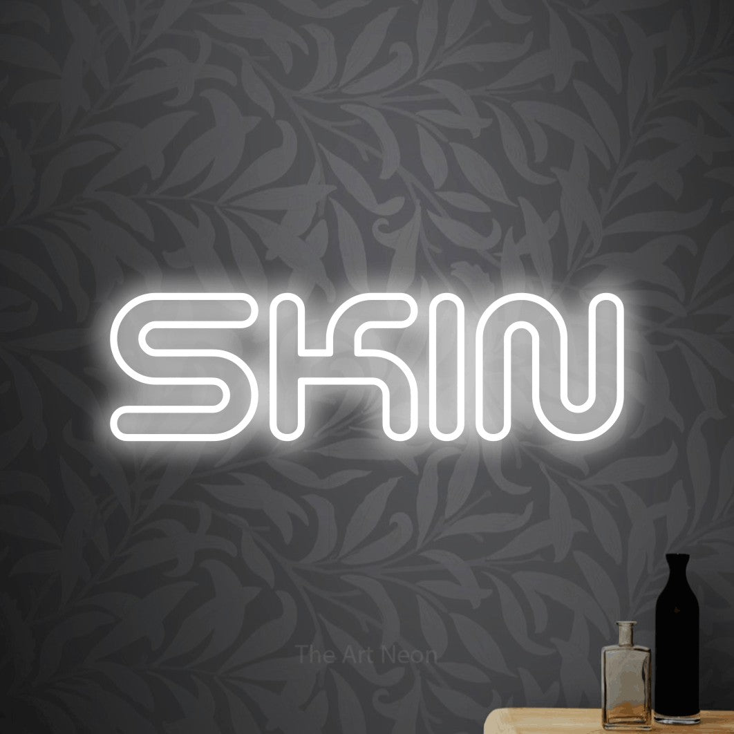 Cool white outline-style LED neon sign reading "Skin" against light grey floral wallpaper for salon décor
