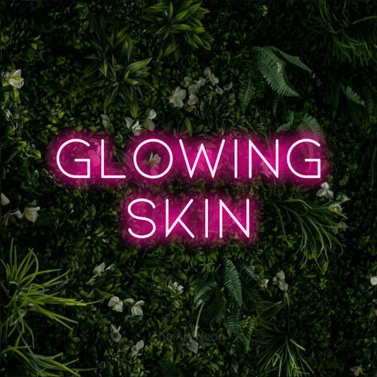 Hot pink LED neon sign reading "Glowing Skin" against a leafy green wall for salon décor