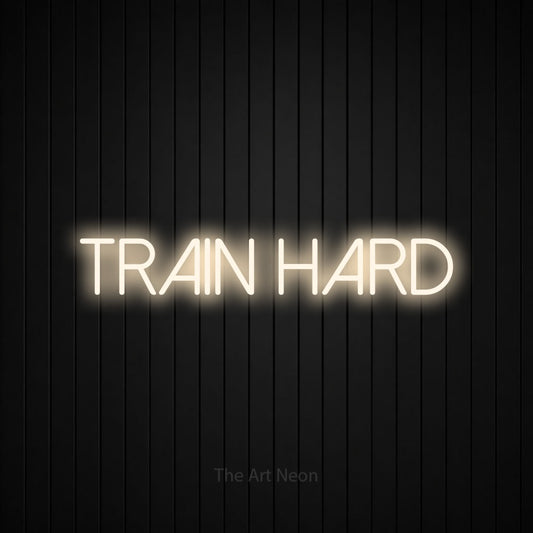 Enseigne néon à DEL à lumière blanche chaude, affichant « Train Hard » sur un mur noir à lattes verticales, pour décorer une salle d’entraînement